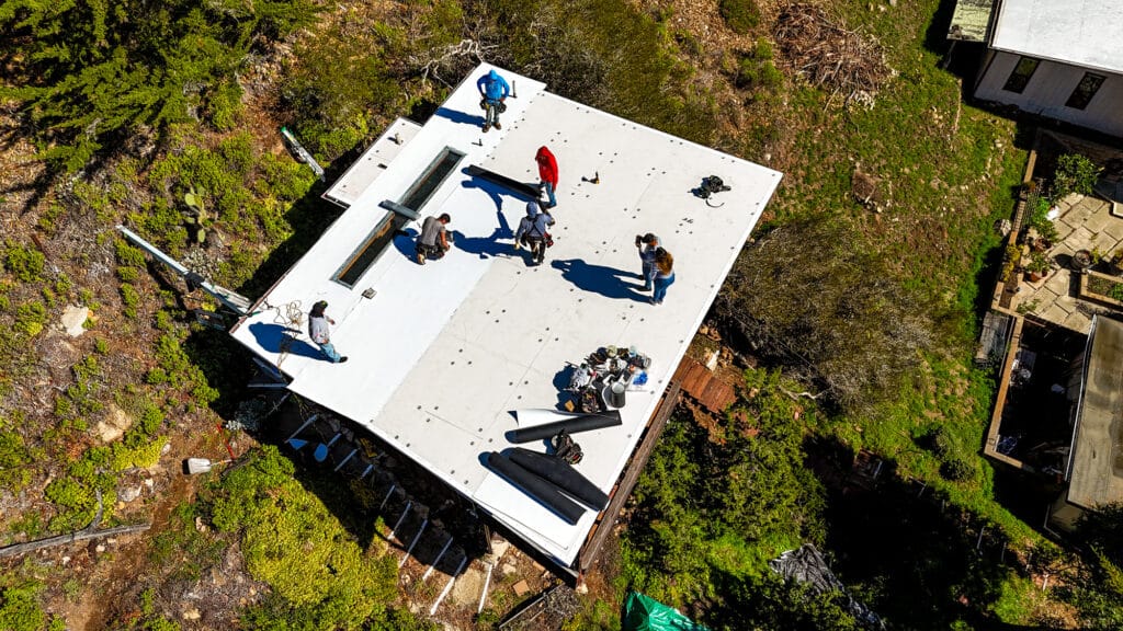 Aerial view of workers on white rooftop.