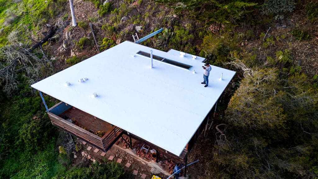 Man standing on white roof in forest