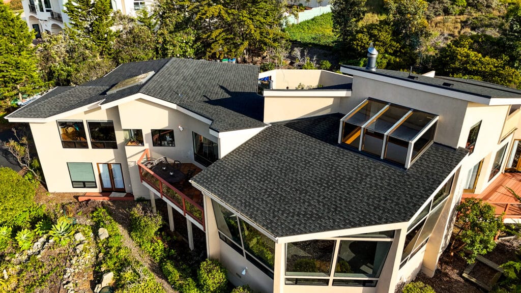 Modern house with black shingle roof and large windows.