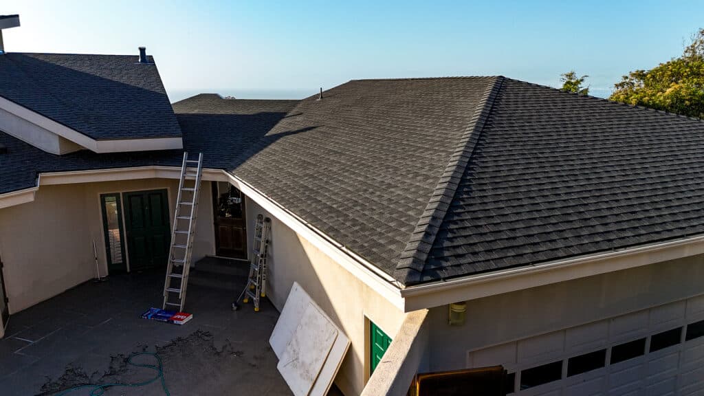 Gray shingle roof with ladder and open doors.