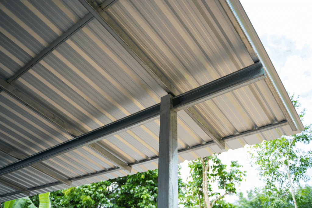 Metal roof structure with trees in background.